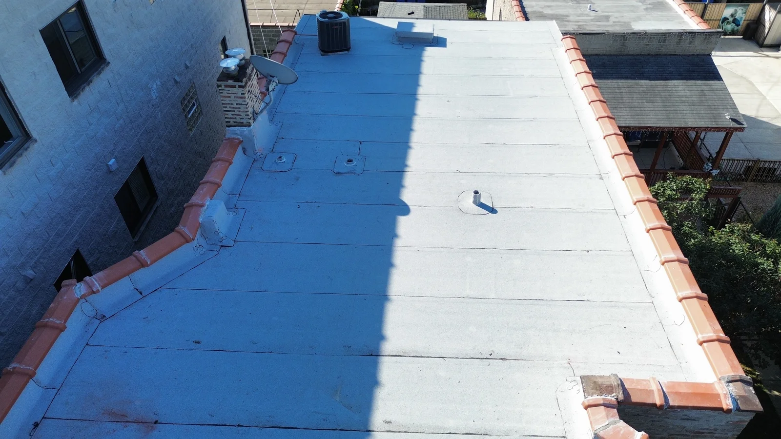 Flat roof half coated in white beside clay coping in Chicago