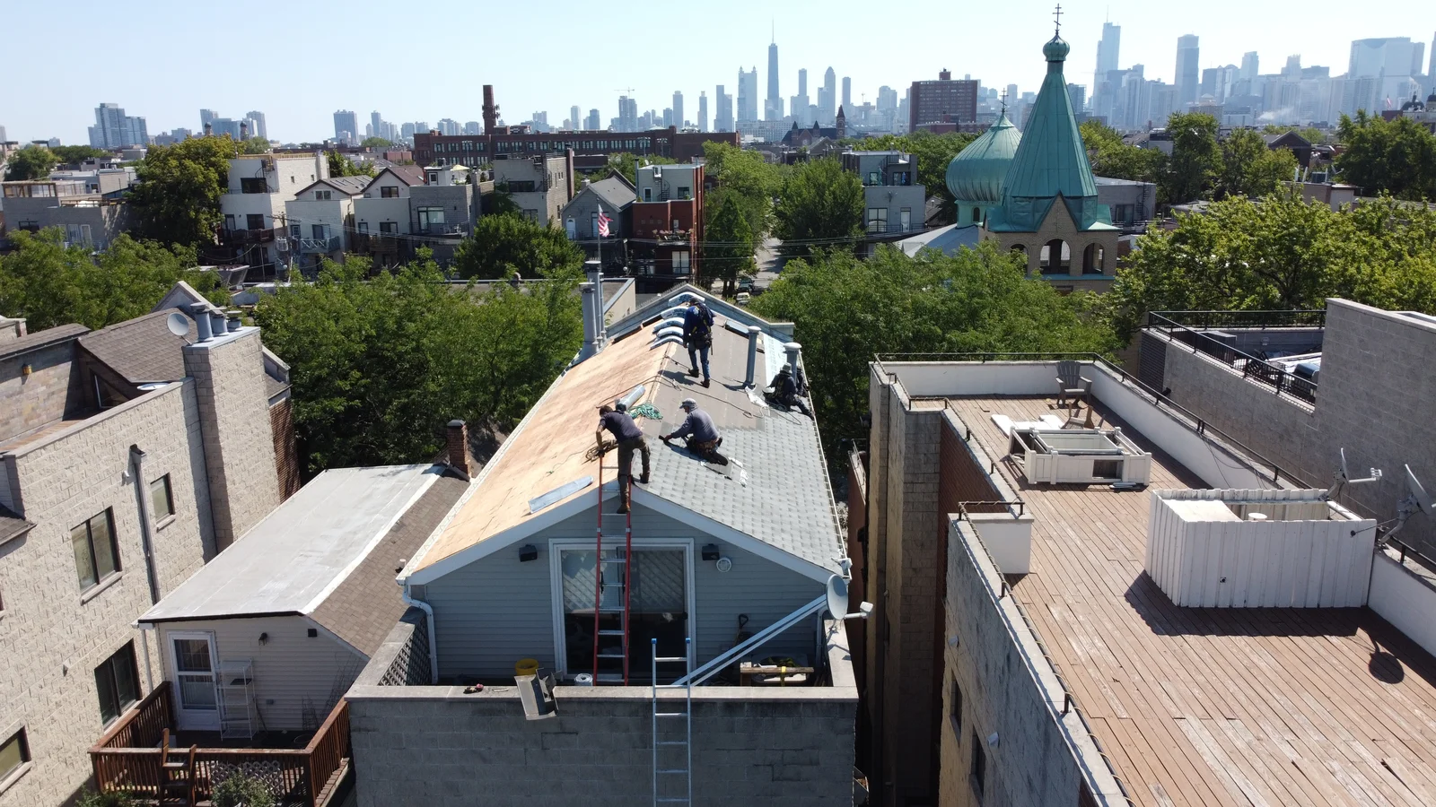 Coating crew on a Chicago two-flat with the skyline behind